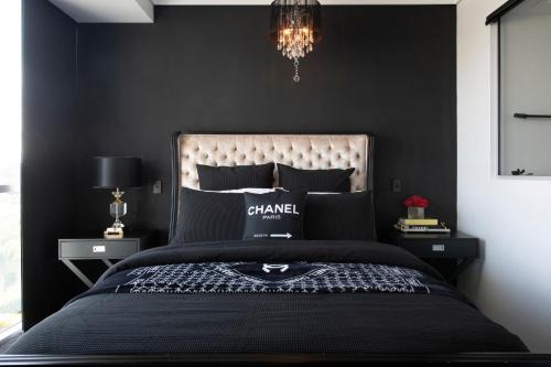 a bedroom with a bed with black walls and a chandelier at Couture Comfort - Luxe Chanel Themed Apartment in Gold Coast