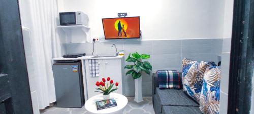 a small room with a couch and a tv on the wall at Dukes Suites in Nairobi