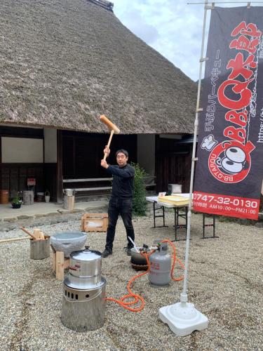 a man holding a baseball bat in front of a building at KANAU in Gojō
