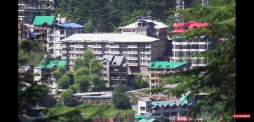 a group of buildings in a city with trees at Ishaan Resort in Manāli