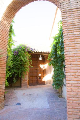 an archway leading to a building with a wooden door at Hospedería Convento de Santa Clara in Palma del Río