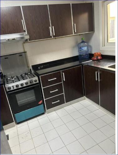 a kitchen with wooden cabinets and a stove top oven at Studio Flat in AWS in Dubai