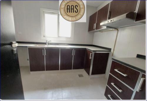 a kitchen with brown cabinets and a plate on the wall at Studio Flat in AWS in Dubai