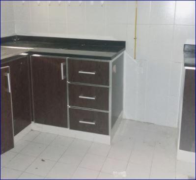 a kitchen with brown cabinets and a counter top at Studio Flat in AWS in Dubai