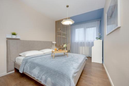 a bedroom with a bed with a table on it at Blue Apartment Słowackiego with Balcony and Parking in Gdańsk by Renters in Gdańsk