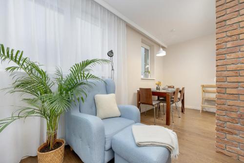 een woonkamer met een blauwe stoel en een plant bij Blue Apartment Słowackiego with Balcony and Parking in Gdańsk by Renters in Gdańsk