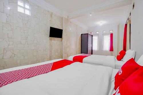 two beds in a room with red and white at OYO Life 90035 Merci Club in Bandung