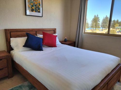 1 dormitorio con 1 cama con 2 almohadas y ventana en Surfside Sunset, en Safety Bay