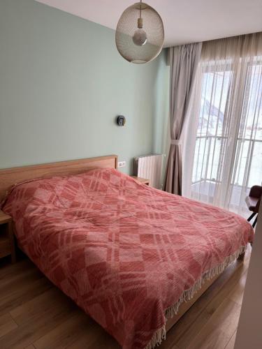 a bedroom with a bed with a red comforter at Cozy one bedroom apartment in New Gudauri in Gudauri
