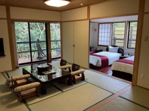 Zimmer mit einem Schlafzimmer, einem Bett und einem Tisch in der Unterkunft Jomon no Yado Manten in Yakushima