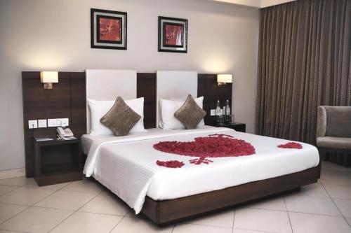 a bedroom with a large bed with red flowers on it at Peerless Hotel Durgapur in Durgāpur