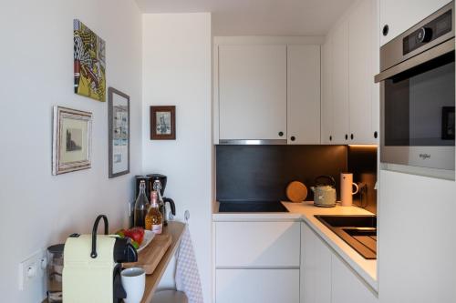 cocina con armarios blancos y microondas negro en ROOFTOP en Ostende