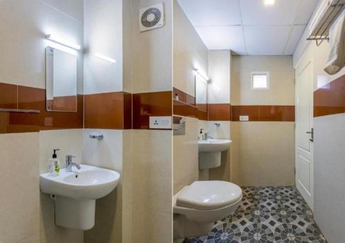 a bathroom with two sinks and a toilet and a mirror at Airport Avenue Plaza Cochin Airport in Nedumbassery