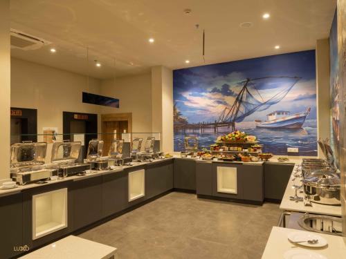 a restaurant with a large painting of a boat on the wall at Luxo Kochi in Ernakulam
