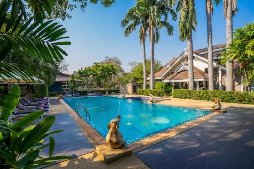 a pool at a resort with monkeys in the water at Le Charme Sukhothai Historical Park - SHA Extra Plus in Sukhothai