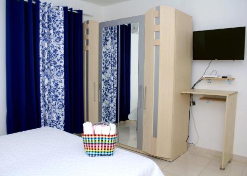 a room with a bed with blue curtains and a television at Complejo Giraflor in Pantoja