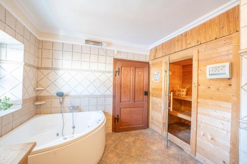 baño con bañera y puerta de madera en Landhaus Krämer, en Lessach