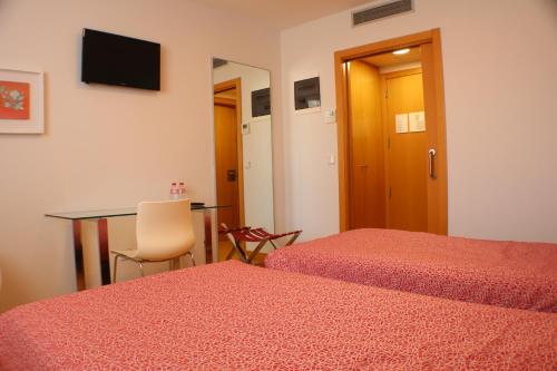a room with two beds and a table and a desk at Hotel Picos De Europa in Santander