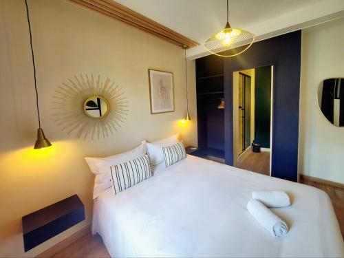 une chambre avec un lit blanc et un miroir dans l'établissement L'Olivier F2 de standing au cœur du vieux Pontoise, à Pontoise