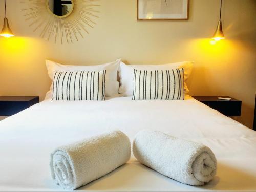 une chambre avec un lit blanc avec deux serviettes dessus dans l'établissement L'Olivier F2 de standing au cœur du vieux Pontoise, à Pontoise