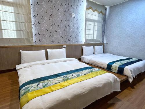 two beds sitting next to each other in a room at Fulong Hotel in Zhongli