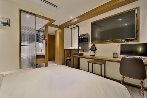 釜山的住宿－Hotel Brooks Busan Gijang，一间卧室配有一张床和一张书桌及电视