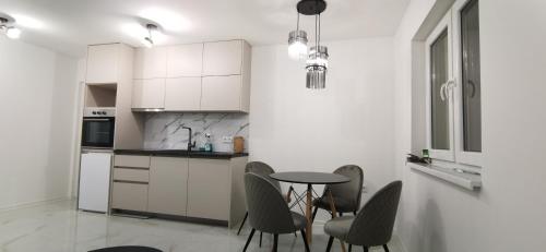 a kitchen with white cabinets and a table and chairs at Apartman Marina stan na dan in Prijedor