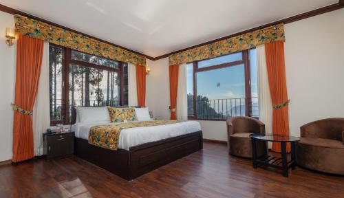 a bedroom with a bed and a large window at Summit Sherpa Mountain Hotel & Spa in Kalimpong