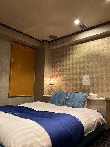 a bedroom with a large bed with blue pillows at Hotel Angel (Adult Only) in Yokohama