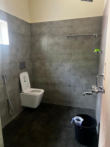 uma casa de banho com um WC e um caixote do lixo preto em Coorg Coffee Inn em Suntikoppa