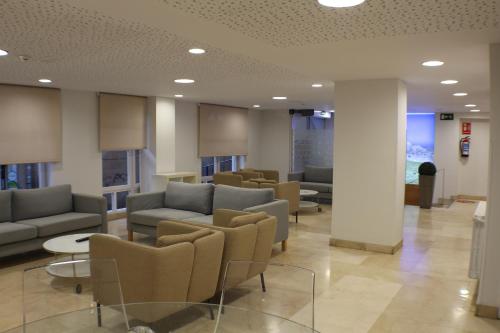 a waiting room with couches and tables and chairs at Hotel Picos De Europa in Santander