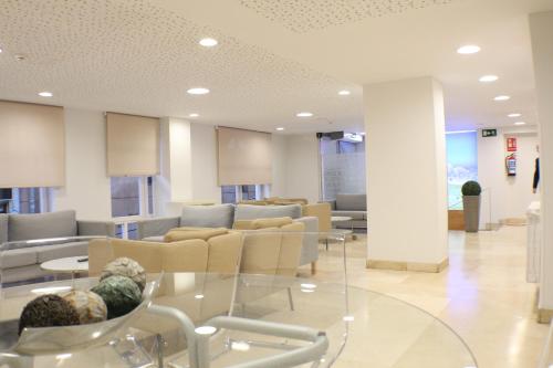 a waiting room with chairs and a glass table at Hotel Picos De Europa in Santander