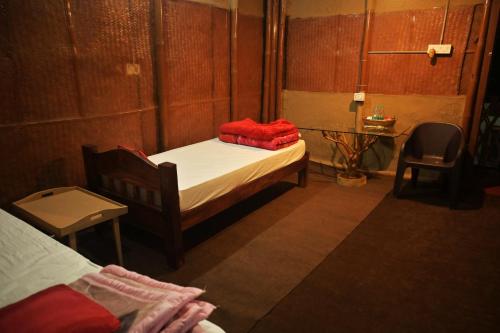 Habitación pequeña con 2 camas y silla en Gorh Retreat, en Kāziranga