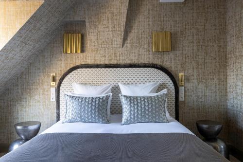 a bedroom with a bed with blue and white pillows at Hotel des Carmes by Malone in Paris