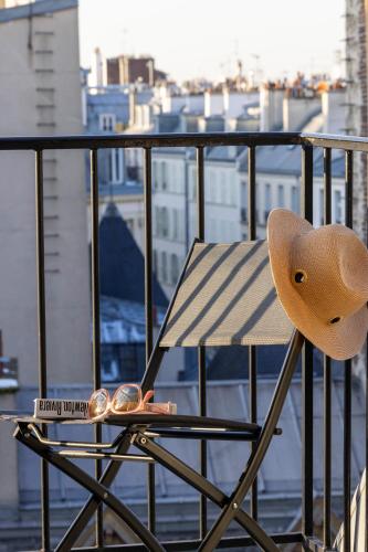 a chair with a hat sitting on a balcony at Hotel des Carmes by Malone in Paris