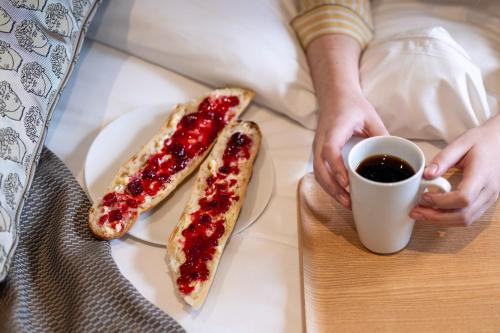 a person holding a cup of coffee and two hot dogs at Hotel des Carmes by Malone in Paris