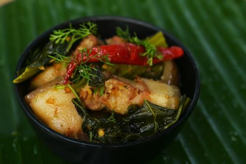 un tazón negro de comida con verduras y carne en Gorh Retreat, en Kāziranga