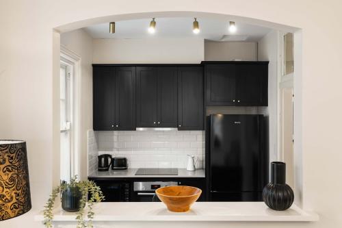 a kitchen with black cabinets and a black refrigerator at Boutique Apartment With Private Roof Terrace in Sydney