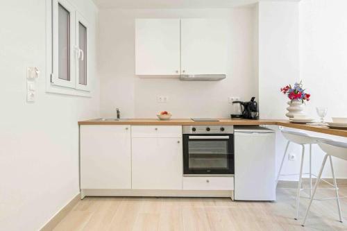 a white kitchen with white cabinets and a counter at E&G Figareto apartments 10 in Kanoni