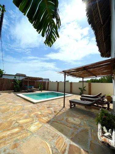 a patio with a swimming pool and a roof at Chunga Changa in Matemwe