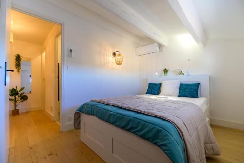 - une chambre blanche avec un lit et des oreillers bleus dans l'établissement Grau Du Roi, au Grau-du-Roi