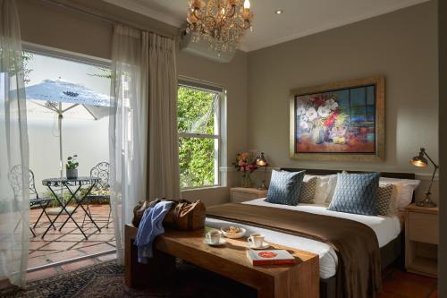 a bedroom with a bed and a table and a window at Spanish Farm Boutique Hotel & Villas in Somerset West