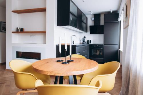 a dining room with a wooden table and yellow chairs at Seaside Apartment in Liepāja