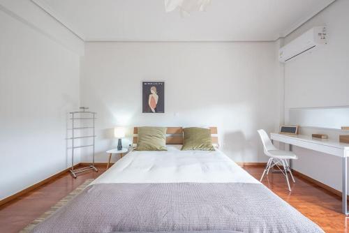 a white bedroom with a large bed and a desk at Open -view Apartment, YGEIA Hospital in Athens