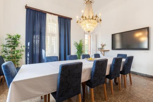 a dining room with a white table and blue chairs at Villa Maresme in Cabrils