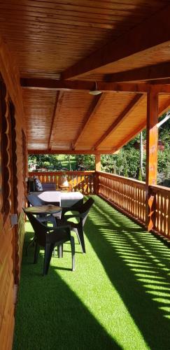a wooden deck with a table and chairs on the grass at Cabana Anisoara-Rimetea in Rimetea