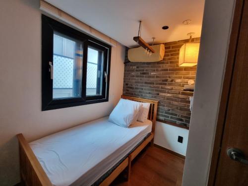 - un petit lit dans une chambre dotée d'un mur en briques dans l'établissement Hwon Guesthouse, à Séoul