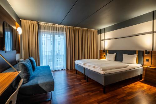 um quarto de hotel com uma cama e um sofá azul em Comfort Hotel Vesterbro em Copenhaga
