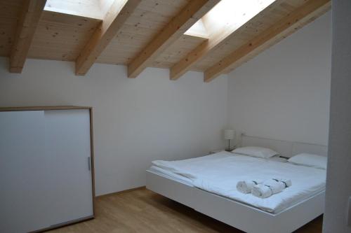 um quarto com uma cama branca e tectos em madeira em Gasthof Faust em Vols am Schlern