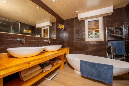 サン・テティエンヌ・ド・ティネにあるChalet Gemme - Magnifique chalet piscine saunaのバスルーム(シンク2台、バスタブ付)